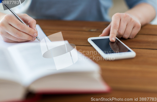 Image of close up of student with smartphone and notebook