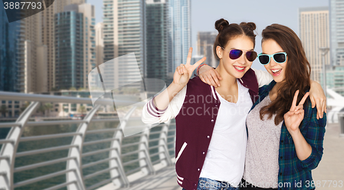 Image of smiling teenage girls in sunglasses showing peace