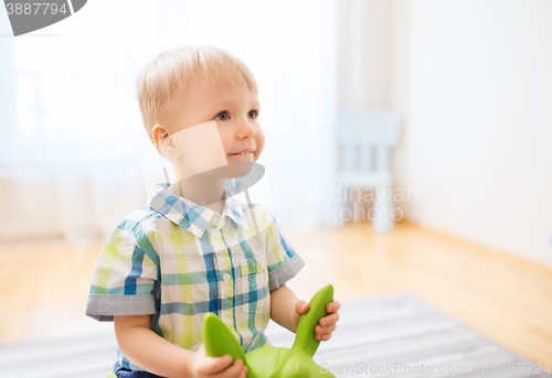 Image of happy baby boy playing with ride-on toy at home