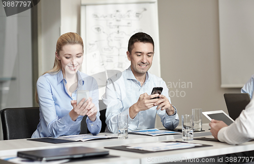 Image of smiling business people with smartphones in office