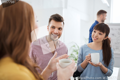 Image of happy creative team drinking coffee at office