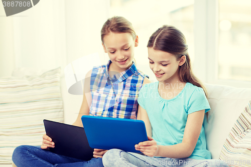 Image of happy girls with tablet pc sitting on sofa at home