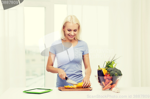 Image of smiling young woman cooking vegetables at home