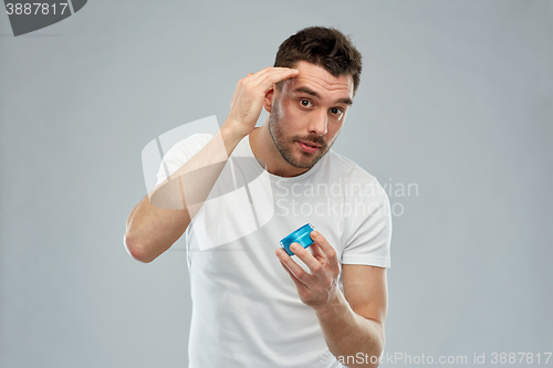Image of happy young man styling his hair with wax or gel