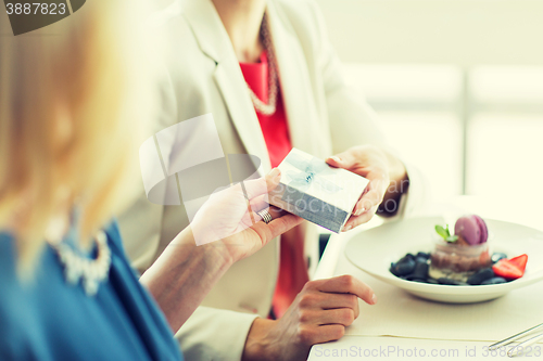 Image of close up of women giving present at restaurant