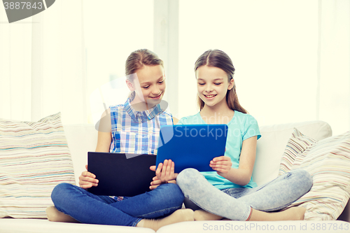 Image of happy girls with tablet pc sitting on sofa at home