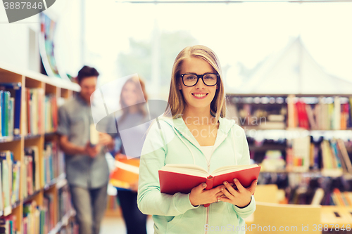 Image of happy student girl or woman with book in library