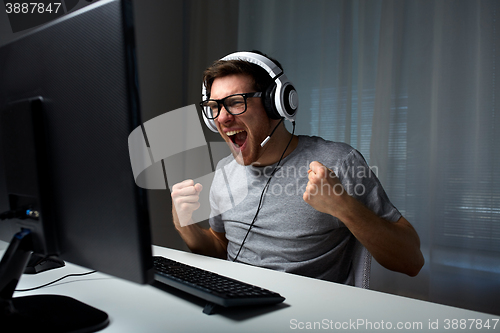 Image of man in headset playing computer video game at home