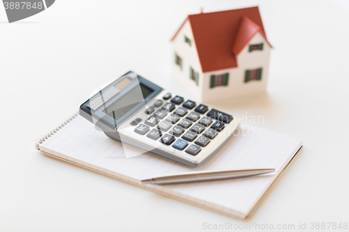 Image of close up of home model, calculator and notebook