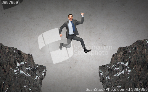 Image of happy smiling businessman jumping between rocks