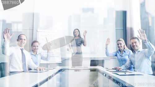 Image of group of businesspeople waving hands in office