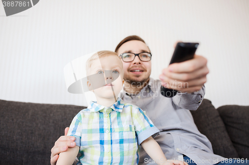 Image of father and son with remote watching tv at home