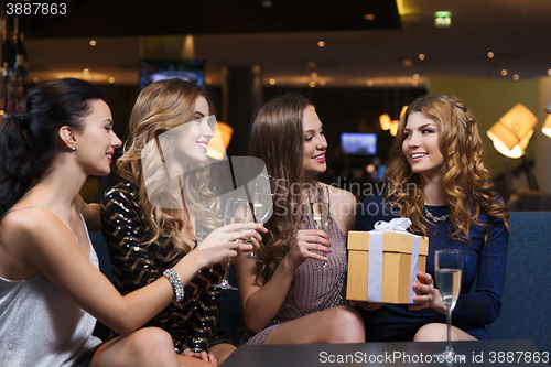 Image of happy women with champagne and gift at night club