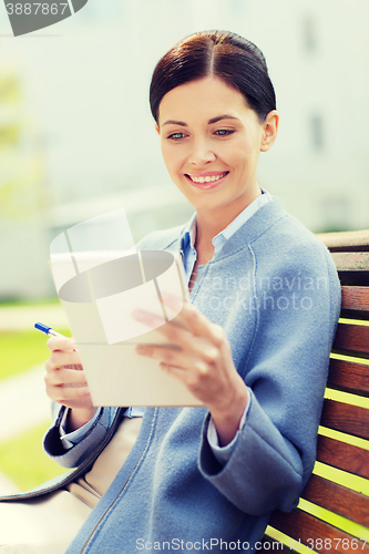 Image of businesswoman reading notes in notepad outdoors