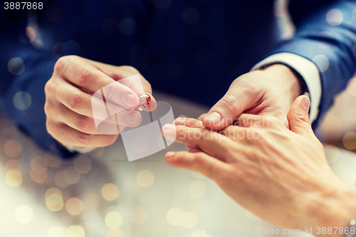 Image of close up of male gay couple hands and wedding ring