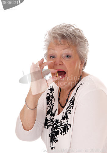 Image of Senior woman swallowing vitamin pill.