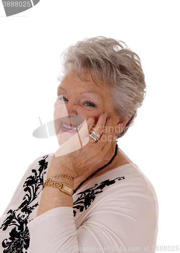 Image of Smiling senior woman holding hand on face.