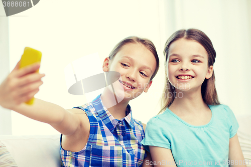 Image of happy girls with smartphone taking selfie at home