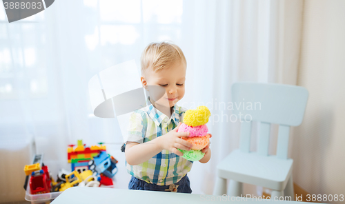 Image of happy little baby boy with ball clay at home