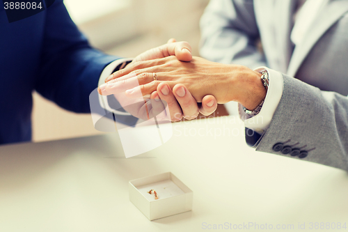 Image of close up of male gay couple hands and wedding ring