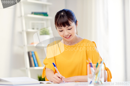 Image of happy asian young woman student learning at home