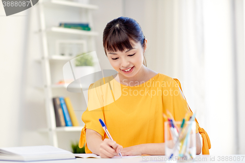 Image of happy asian young woman student learning at home