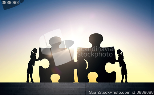Image of silhouette of two business women connecting puzzle