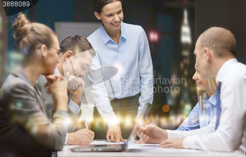 Image of smiling female boss talking to business team