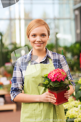 Image of happy woman holding flowers in greenhouse