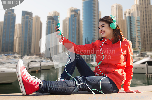 Image of happy young woman with smartphone and headphones