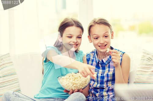 Image of happy girls with popcorn watching tv at home