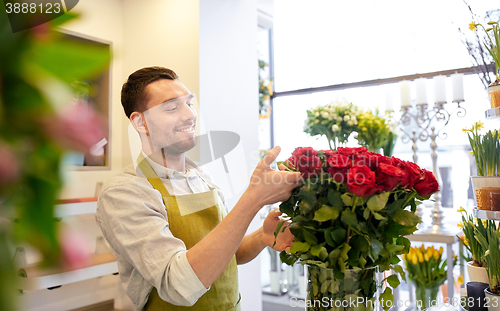 Image of smiling florist man with roses at flower shop