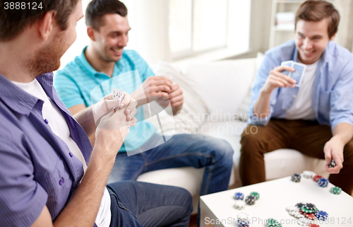 Image of close up of male friends playing cards at home