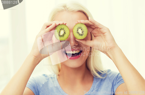 Image of happy woman having fun covering eyes with kiwi