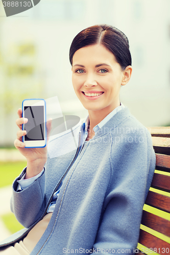 Image of young smiling businesswoman showing smartphone