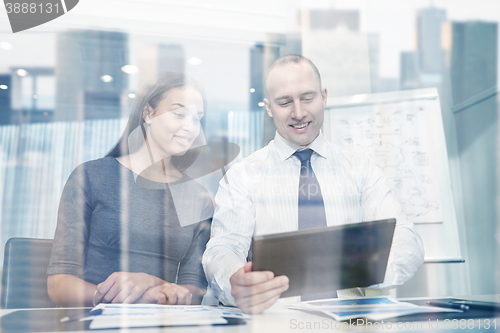 Image of smiling businesspeople with tablet pc in office