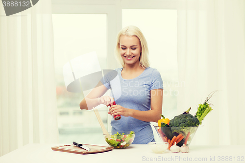 Image of smiling woman cooking vegetable salad at home