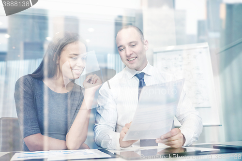 Image of smiling businesspeople with papers in office