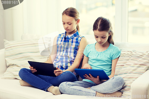 Image of girls with tablet pc sitting on sofa at home