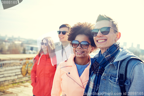 Image of happy teenage friends in shades hugging on street