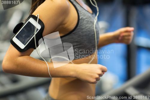 Image of woman with smartphone and earphones in gym