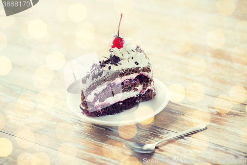 Image of piece of cherry chocolate cake on wooden table