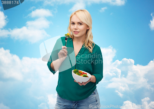 Image of smiling young woman eating vegetable salad