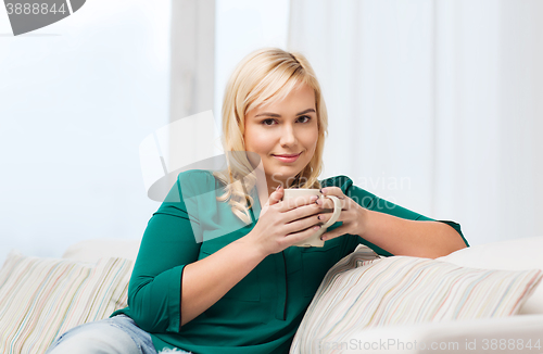 Image of happy woman  with cup of tea or coffee at home