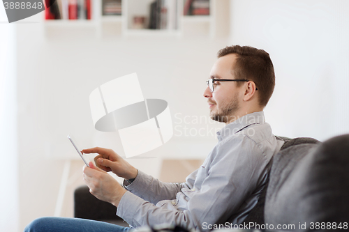 Image of smiling man working with tablet pc at home