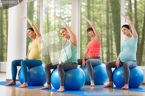 Image of happy pregnant women exercising on fitball in gym