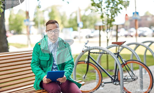 Image of sad young hipster man with tablet pc and bike