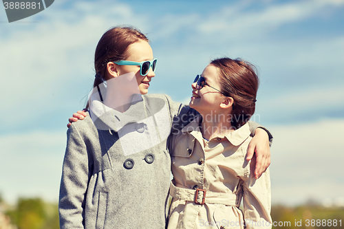 Image of happy little girls hugging and talking outdoors