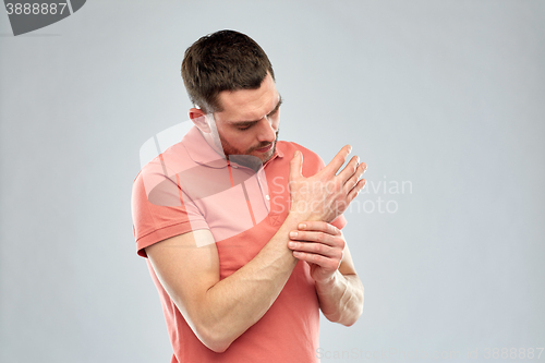 Image of unhappy man suffering from pain in hand