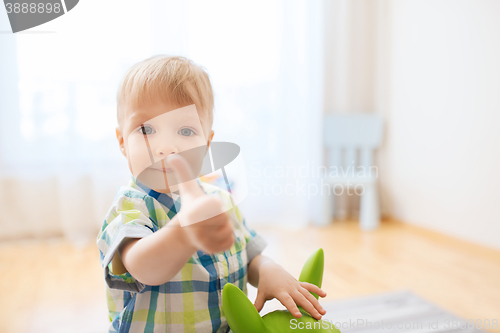 Image of happy baby boy playing with toy showing thumbs up